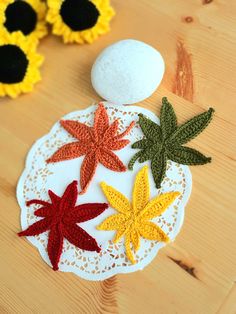 crocheted autumn leaves are on a doily next to an egg and flowers