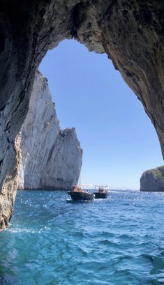 an image of a boat in the water through a cave with rocks on either side