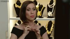 a woman standing in front of a shelf filled with necklaces and bracelets on display