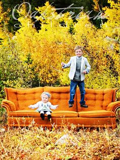 two young boys standing on an orange couch in the middle of a field with yellow flowers