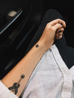 a woman's arm with a guitar tattoo on it