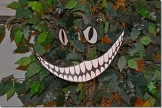 a fake smile made out of paper sitting on top of a green leafy tree