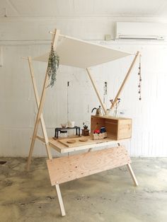 a wooden table with a white canopy over it and other items on the top shelf