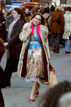 a woman is walking down the street talking on her cell phone while wearing a fur coat