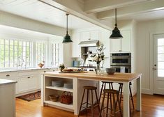 a kitchen with white cabinets and wooden counter tops next to an island in the middle