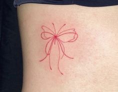 a woman's stomach with a red bow tattoo on it