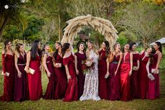 a group of women standing next to each other in front of a wooden arch with flowers on it