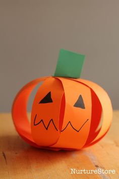 an orange paper pumpkin sitting on top of a wooden table