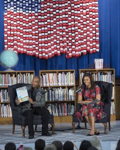 two people sitting on chairs in front of an american flag wall with bookshelves