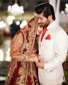 a man and woman dressed in wedding attire standing next to each other with their eyes closed