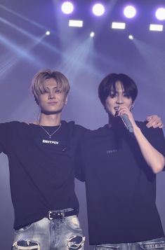 two young men standing next to each other holding microphones in front of their faces