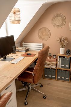 a desk with a computer on top of it in front of an atticed room