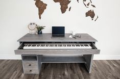 a desk with a keyboard and a laptop on it in front of a world map