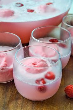 three glasses filled with ice and raspberries next to a bowl full of berries