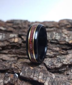 "African Ebony wood ring with a centered band of crushed Garnet gemstone and Bronze inlays. * Made to order in all sizes. * Finished first with tung oil to really bring out the wood grains beauty, then coated with multiple layers of CA achieving a strong high-gloss polish * Extremely durable and water resistant. * Fast worldwide shipping *Shipping* This item includes free domestic and international shipping. Its delivery process takes from 10 to 15 business days and it includes a track & tra Spiritual Black Jewelry For Promise, Black Inlay Jewelry As A Gift, Black Jewelry With Inlay For Gift, Black Ring With Inlay, Black Rings With Inlay, Black Inlay Round Ring, Handmade Black Jewelry For Promise, Handmade Black Promise Jewelry, Black Handmade Promise Jewelry