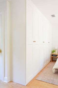 a bedroom with white walls and wooden floors