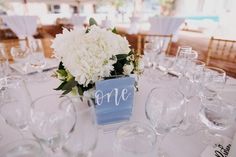 a centerpiece with white flowers and greenery sits on a table at a wedding reception