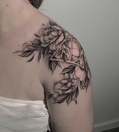 a woman's shoulder tattoo with flowers and leaves on her left arm, in black and white