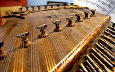 an old musical instrument with many knobs and strings on it's side,