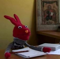 a red stuffed animal sitting on top of a desk