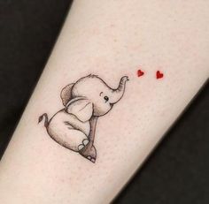 an elephant with a heart tattoo on its leg is sitting in front of a woman's arm