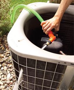 a man is using a hose to fix an air conditioner