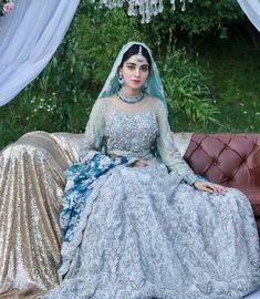 a woman sitting on top of a couch wearing a blue and gold dress with sequins