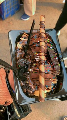 a person holding a large piece of chocolate cake with sprinkles on it