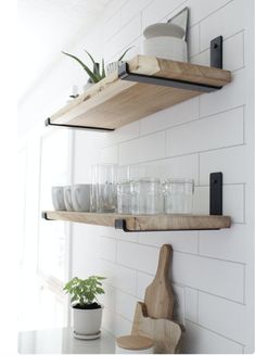 two wooden shelves holding dishes and utensils in a white kitchen with black brackets on the wall