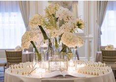 flowers and candles are arranged in vases on a table with an open book next to them