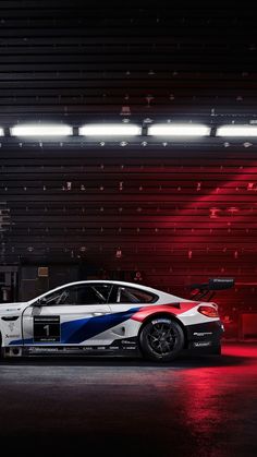 a white car with blue and red stripes on it's side in a garage