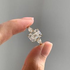 a woman's hand holding an engagement ring with two diamonds on the top and bottom