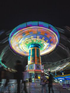 a carnival ride at night with people walking around