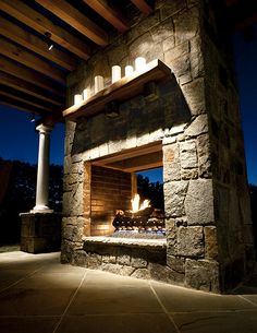 an outdoor fireplace lit up at night with candles