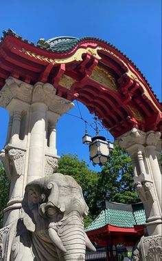 an elephant statue in front of a red and white structure with a clock on top