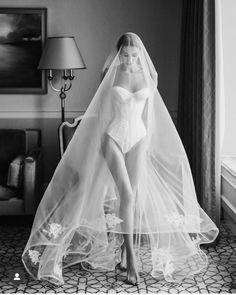 a black and white photo of a woman in a wedding dress with a veil on her head