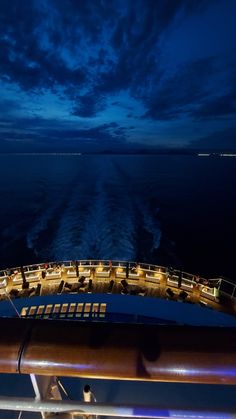 the back end of a boat at night with clouds in the sky and lights on