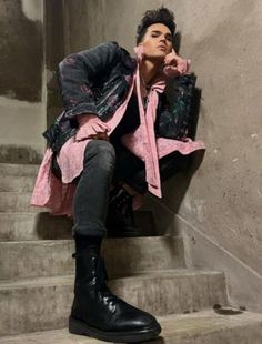 a man sitting on some steps wearing black boots