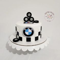 a white cake with black and white stripes on it, topped with a bmw emblem