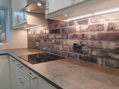 a kitchen with white cabinets and grey brick backsplash