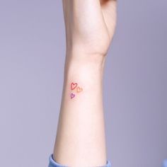 a woman's wrist with two hearts tattooed on the left side of her arm