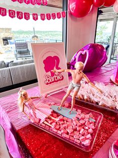 two barbie dolls are standing on top of pink hearts in front of a table full of valentine's day treats