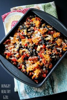 a casserole dish with black beans, cheese and other toppings in it