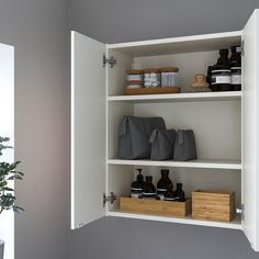 an open cabinet with some items on it and a potted plant in the corner