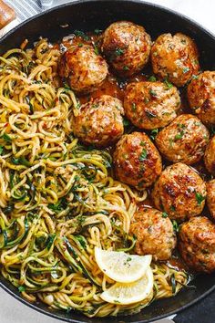 spaghetti and meatballs in a skillet with lemon wedges on the side, ready to be eaten