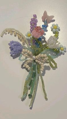 a bouquet of flowers with beads and butterflies on it's back drop off from the wall