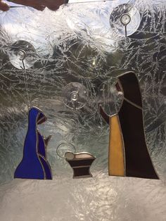 three stained glass nativity scene displayed in front of a frosted window with snow on the ground