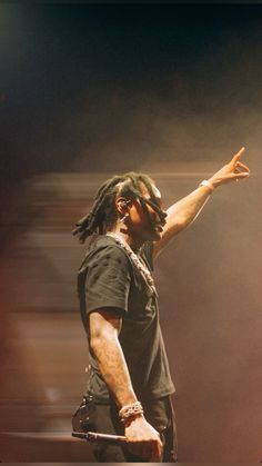 a man with dreadlocks is holding his hand out in the air while standing on stage