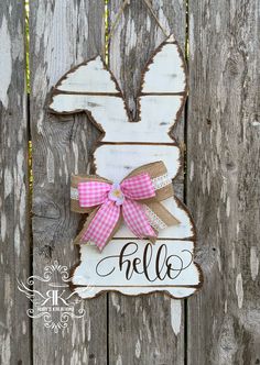 a wooden sign with the word hello written on it and a pink bow tied to it