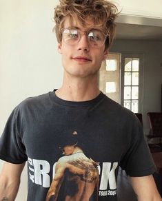 a young man with glasses standing in front of a mirror